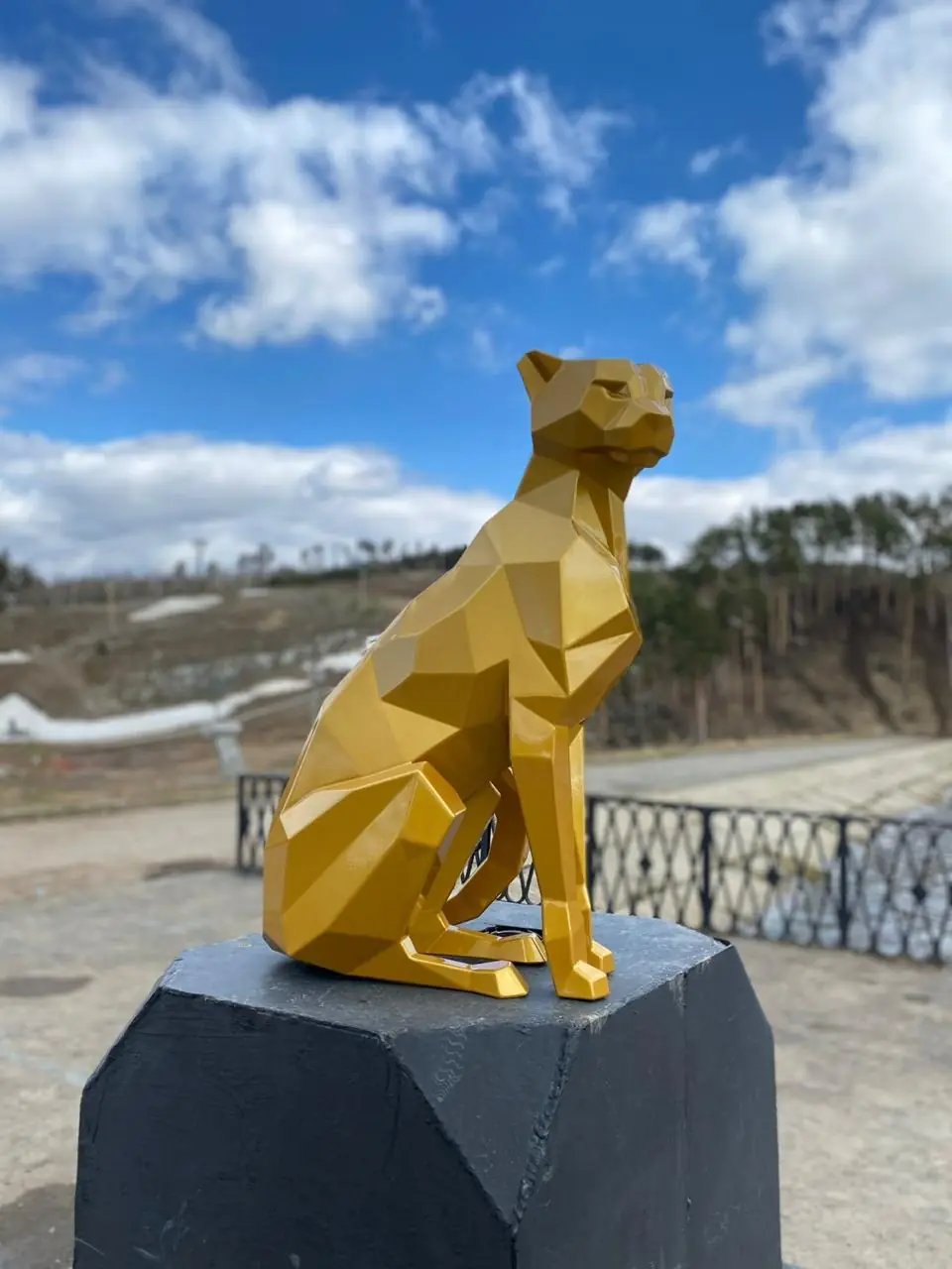 Sculpture de félin polygonale dorée face au paysage